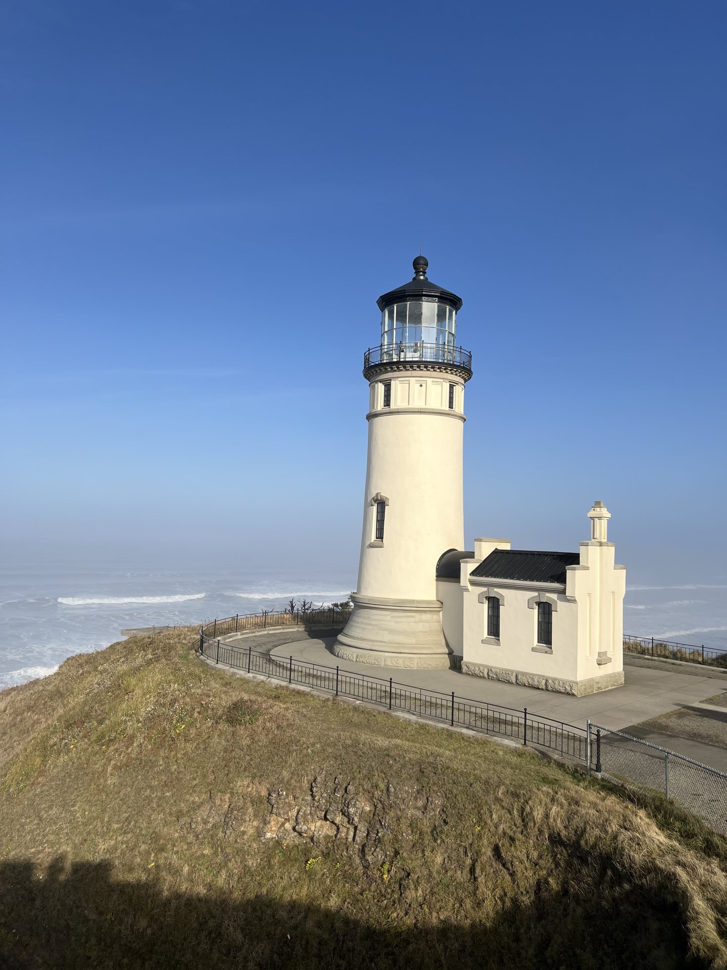 Cape Disappointment Lighthouse on a rocky basalt headland in Washington State, with the Pacific Ocean and Columbia River mouth visible below