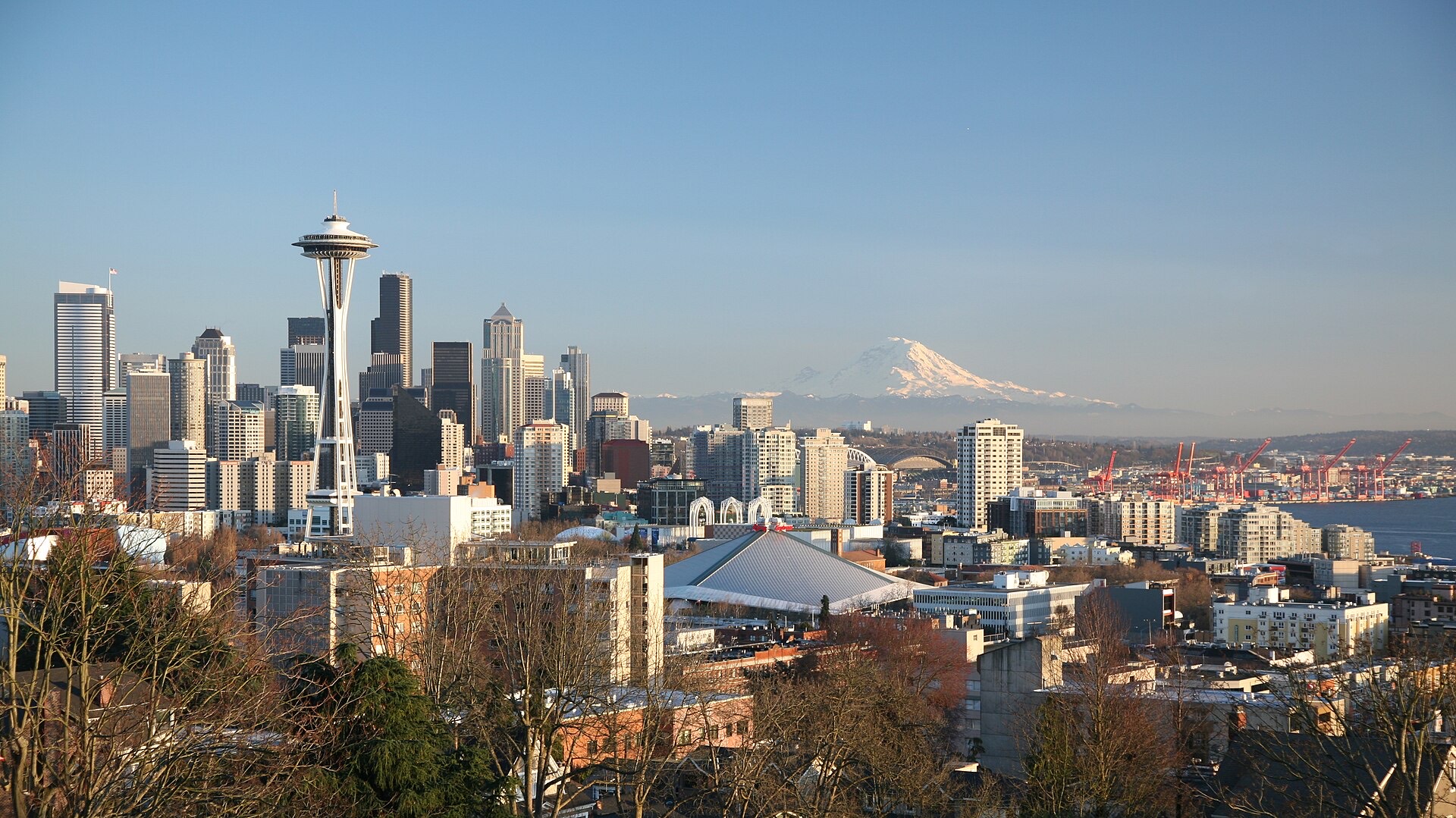 Seattle skyline at sunset with Mount Rainier rising above the city and Puget Sound in the foreground