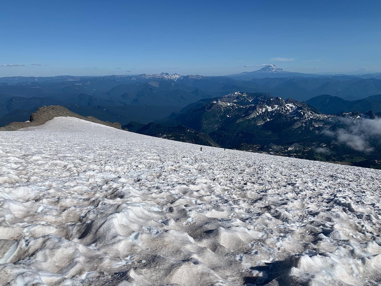 Climbers crossing the Muir Snowfield on Mount Rainier with Mount Adams on the horizon