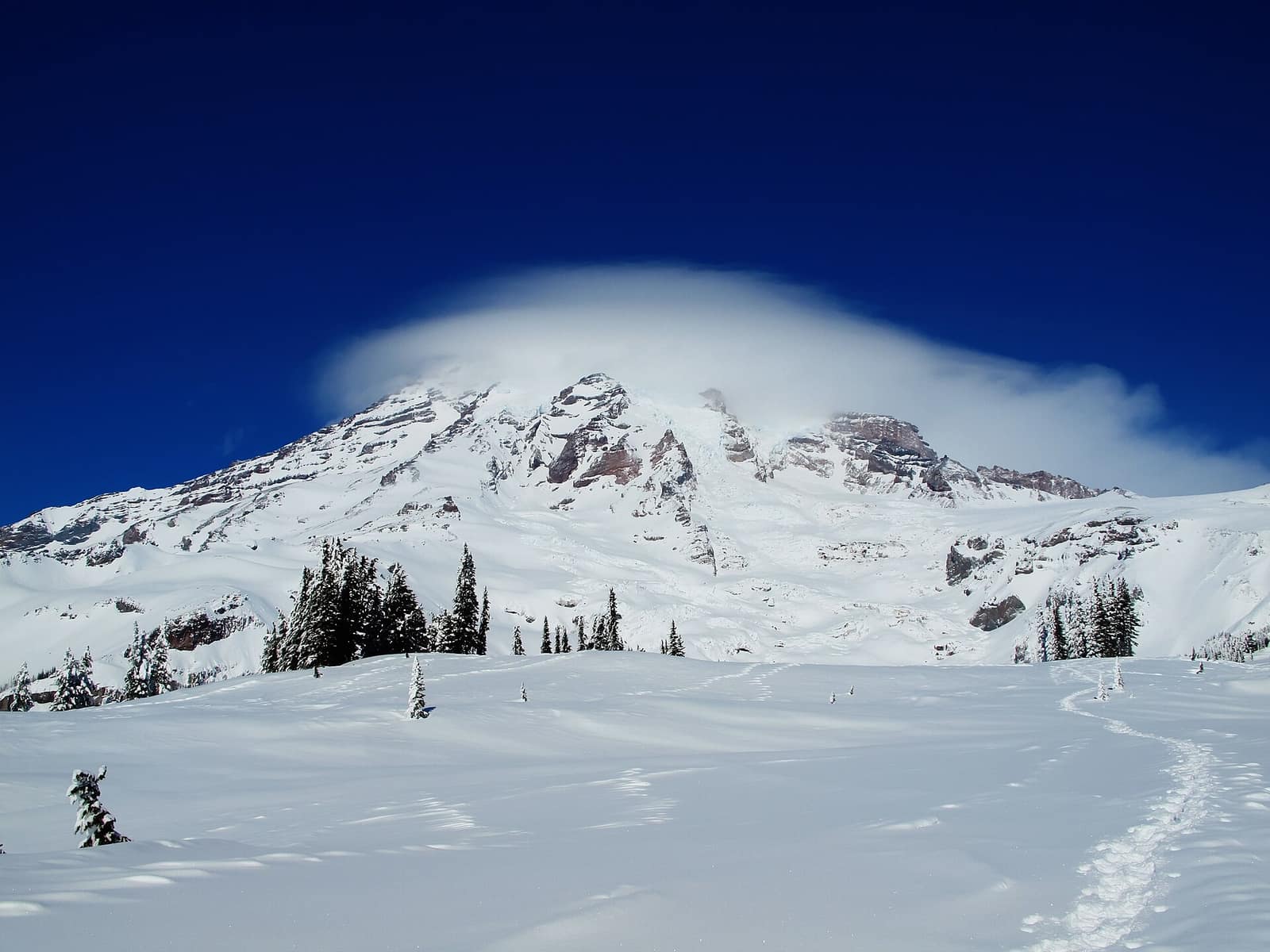 Lenticular cloud capping Mount Rainier above snow-covered Paradise in winter