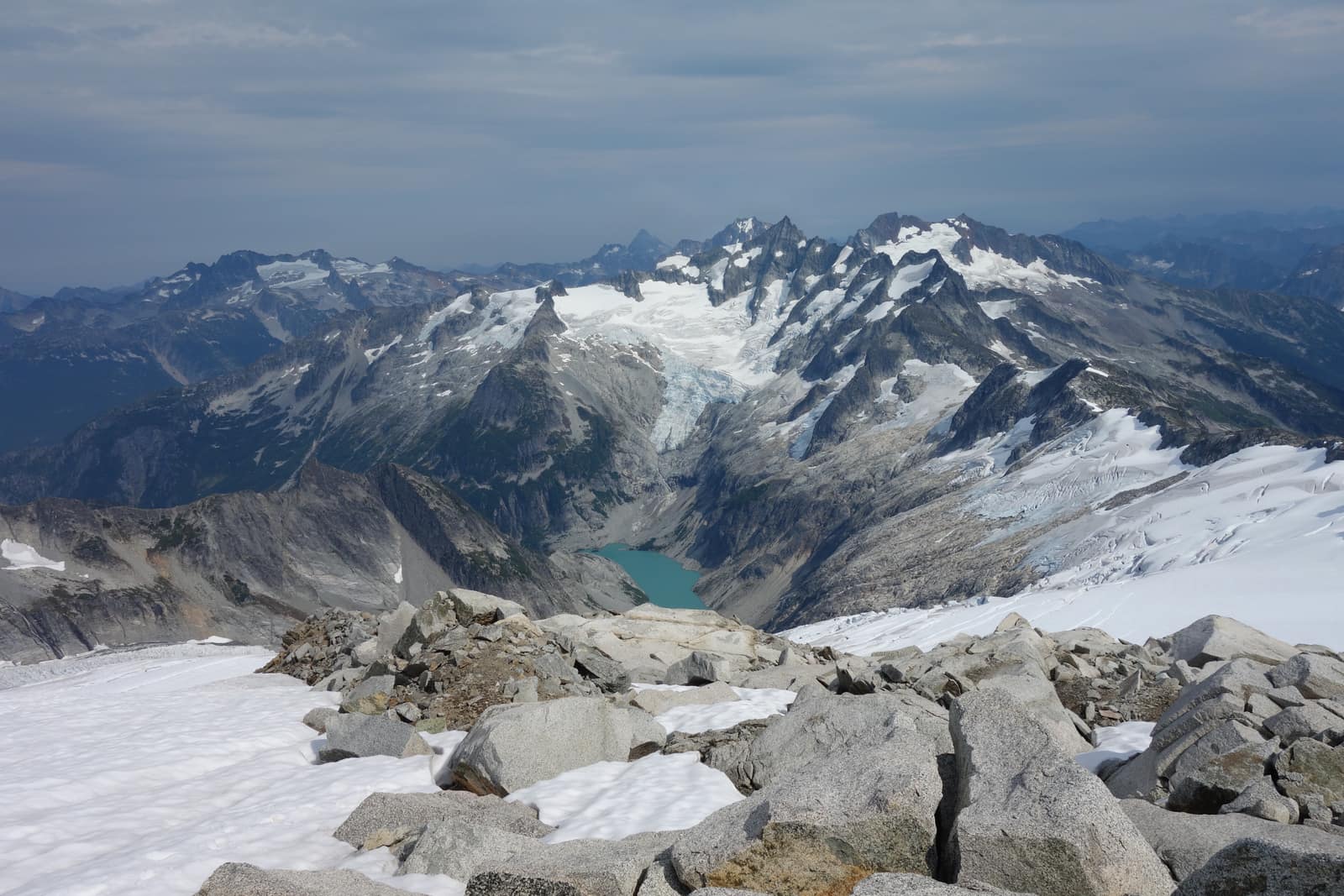 Aerial view of North Cascades National Park showing jagged glaciated peaks, a turquoise glacial lake, and vast snowfields in Washington State
